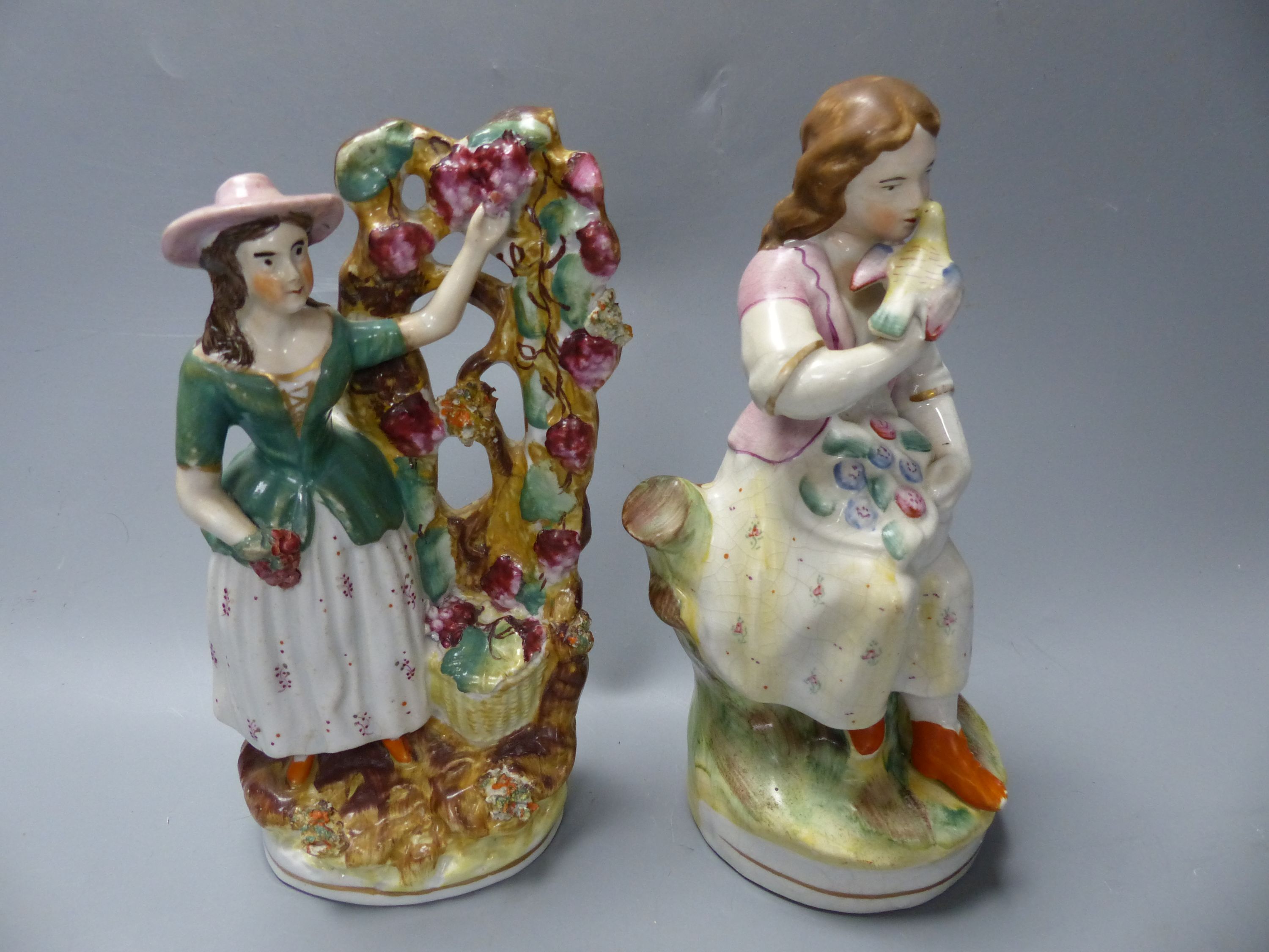 A Staffordshire figure of a female grape picker with vine bocage and three other figures
